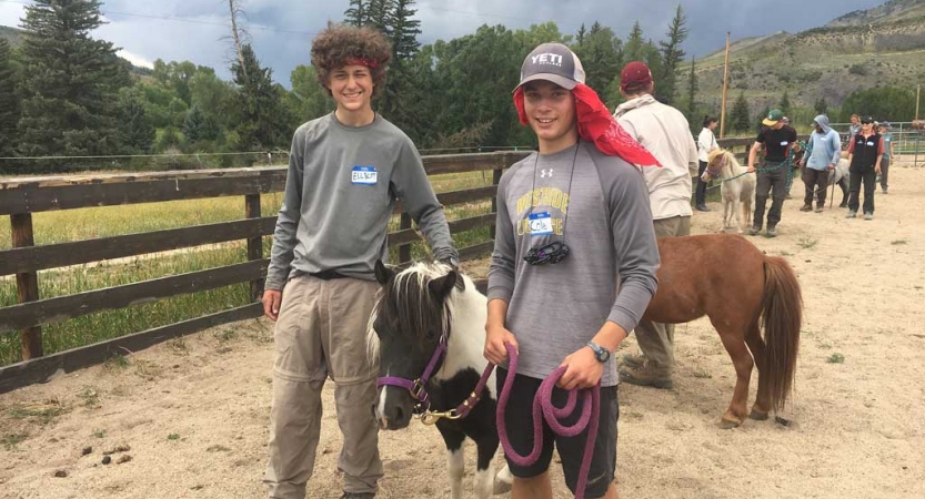 two students hold the lead rope of a mini horse during a service project with outward bound